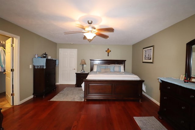 bedroom featuring dark hardwood / wood-style floors, ceiling fan, and a spacious closet