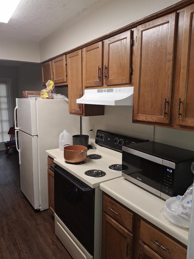 kitchen featuring a textured ceiling, light countertops, stainless steel microwave, under cabinet range hood, and electric stove