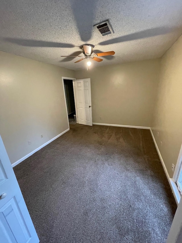 unfurnished room featuring a textured ceiling, ceiling fan, and dark colored carpet