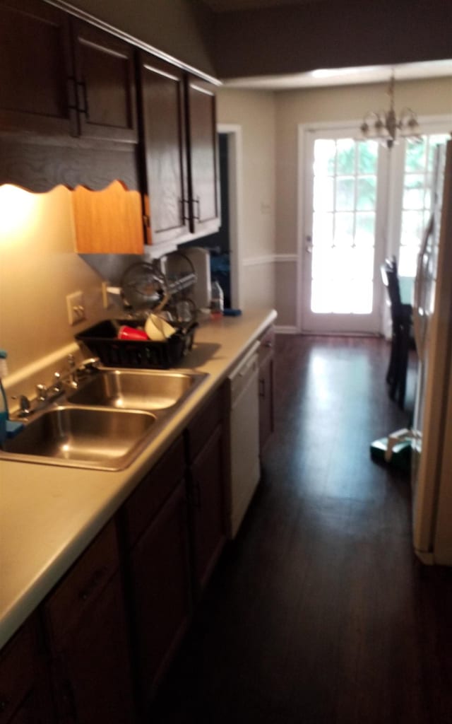 kitchen featuring sink, hanging light fixtures, dark wood-type flooring, white dishwasher, and dark brown cabinets