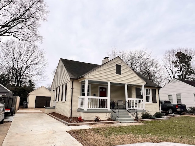 bungalow-style house featuring a front lawn, a porch, an outdoor structure, and a garage