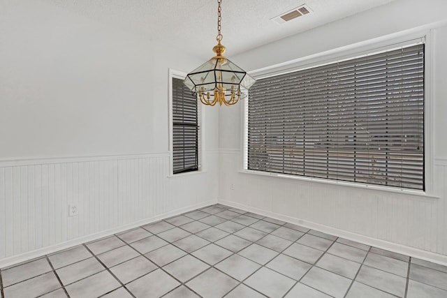 unfurnished room featuring an inviting chandelier and a textured ceiling