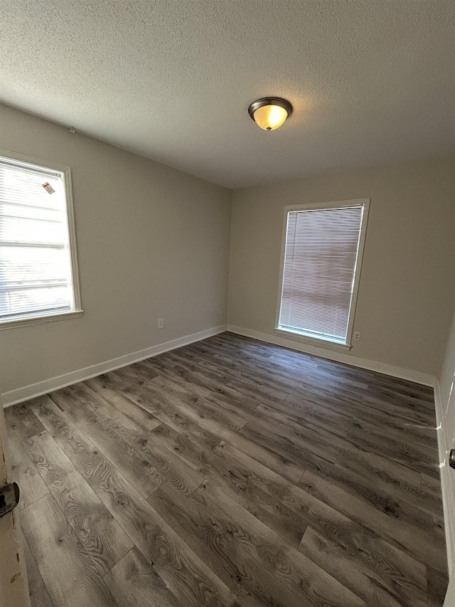 spare room featuring dark wood-type flooring and a textured ceiling