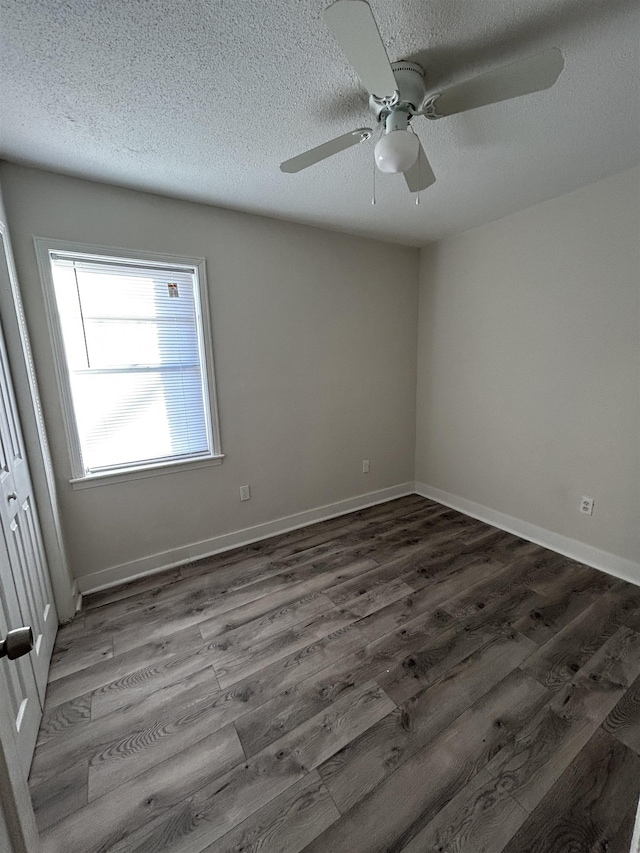 empty room featuring dark wood-type flooring, ceiling fan, and a textured ceiling