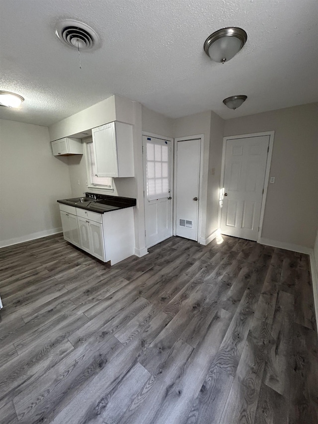 kitchen featuring white cabinetry, sink, hardwood / wood-style floors, and a textured ceiling