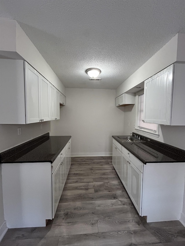 kitchen featuring dark hardwood / wood-style flooring, sink, a textured ceiling, and white cabinets