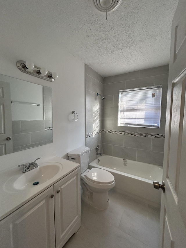 full bathroom featuring toilet, a textured ceiling, vanity, tiled shower / bath combo, and tile patterned flooring