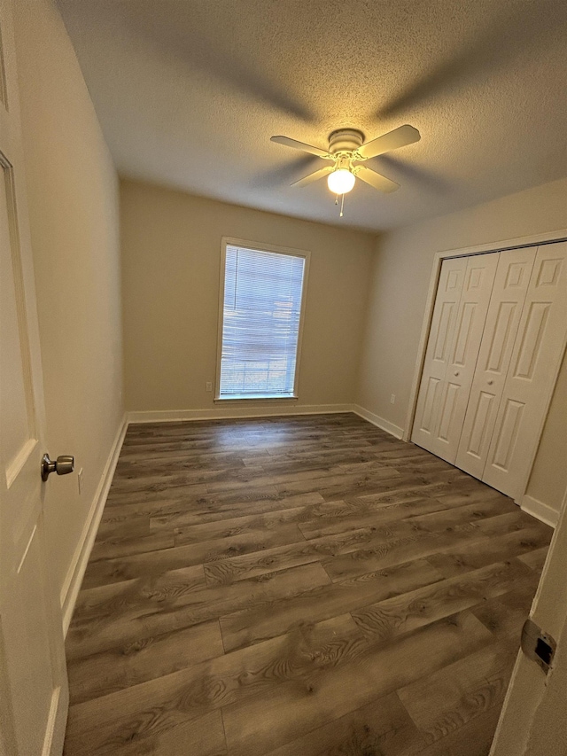 unfurnished bedroom featuring ceiling fan, dark hardwood / wood-style floors, a textured ceiling, and a closet