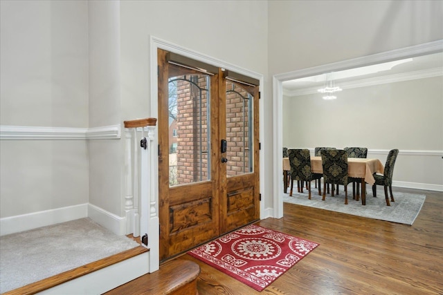 entryway featuring an inviting chandelier, wood-type flooring, crown molding, and french doors