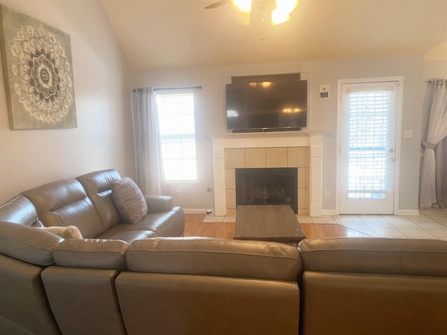 living room featuring vaulted ceiling, ceiling fan, and a fireplace