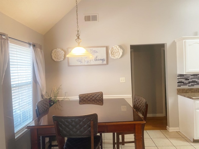 tiled dining space featuring lofted ceiling