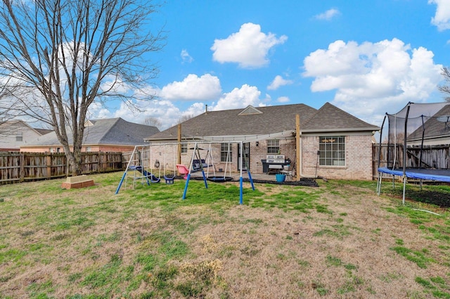 back of house with a playground, a yard, and a trampoline