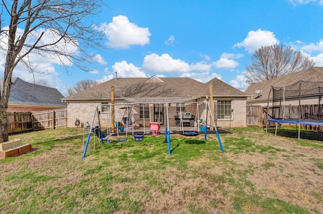 rear view of house with a playground, a trampoline, and a lawn