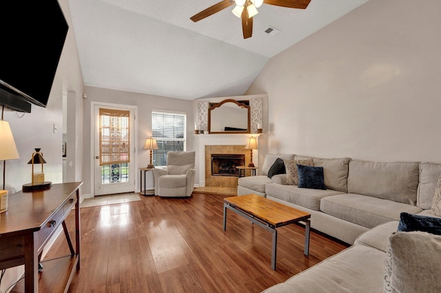 living room featuring a tiled fireplace, hardwood / wood-style floors, high vaulted ceiling, and ceiling fan