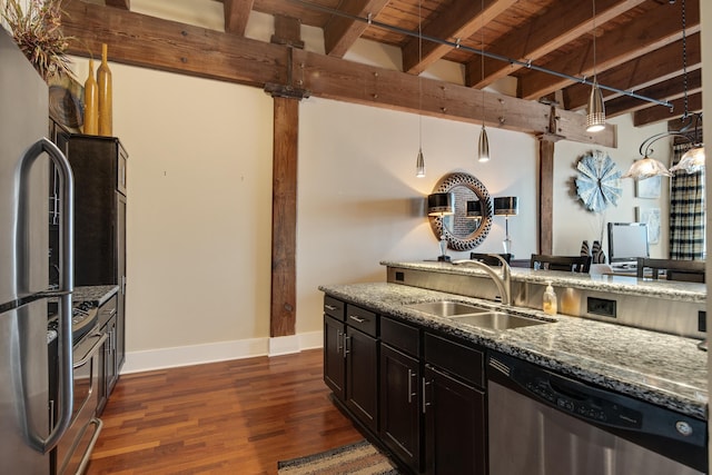 kitchen featuring sink, appliances with stainless steel finishes, dark stone countertops, decorative light fixtures, and beamed ceiling