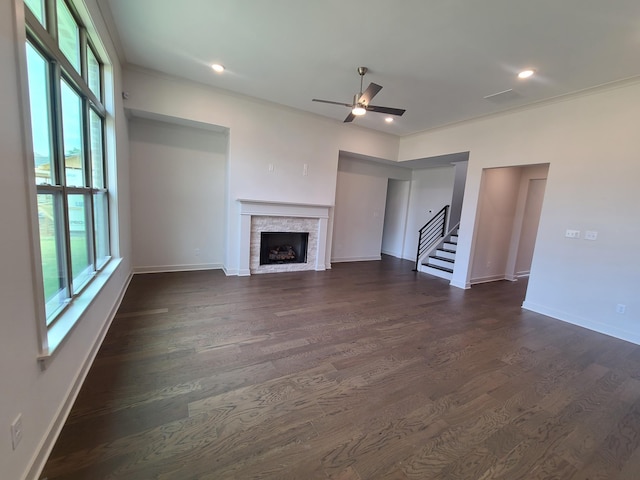 unfurnished living room featuring ceiling fan, ornamental molding, a fireplace, and dark hardwood / wood-style flooring