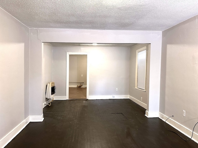 unfurnished room with dark hardwood / wood-style floors, heating unit, and a textured ceiling