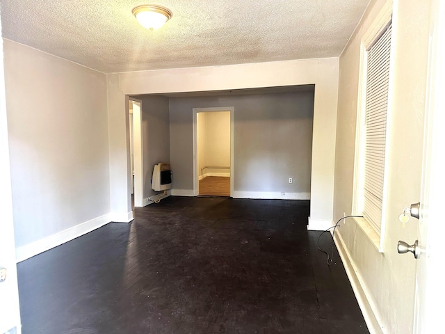 unfurnished room featuring heating unit and a textured ceiling