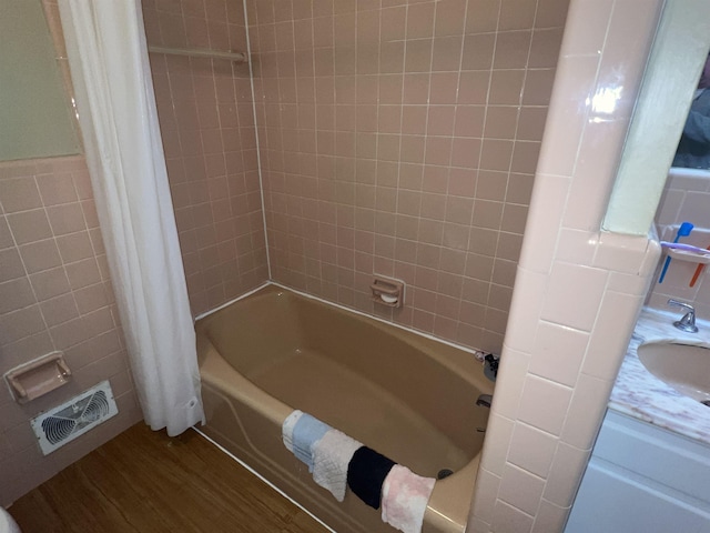 bathroom with tile walls, hardwood / wood-style floors, sink, and shower / bath combo with shower curtain