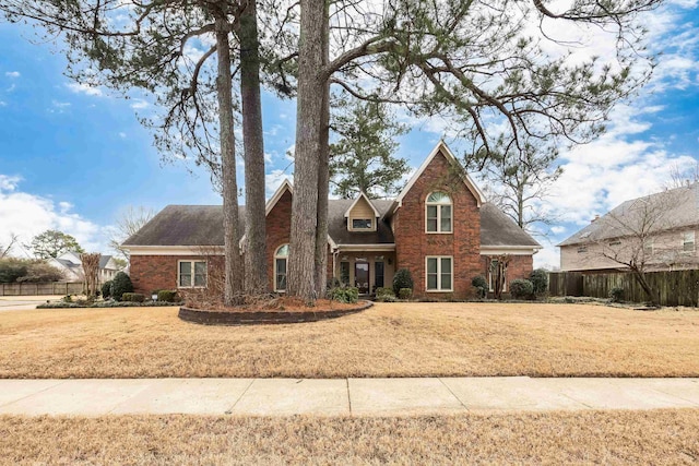 view of front of house featuring brick siding, fence, and a front lawn