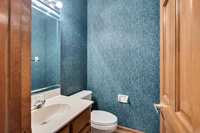 bathroom with toilet, vanity, and baseboards