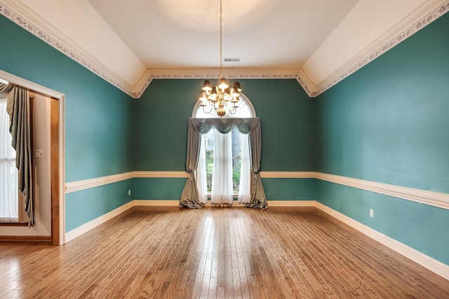 empty room with visible vents, a chandelier, wood-type flooring, lofted ceiling, and baseboards