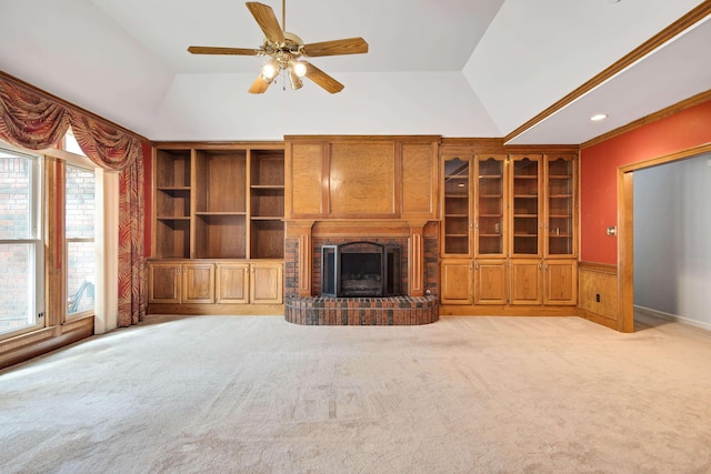 unfurnished living room with built in features, a brick fireplace, a ceiling fan, vaulted ceiling, and light colored carpet