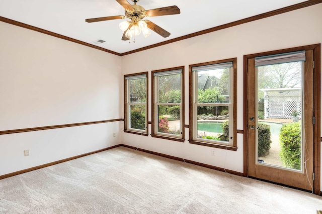empty room with baseboards, ornamental molding, light carpet, a ceiling fan, and visible vents