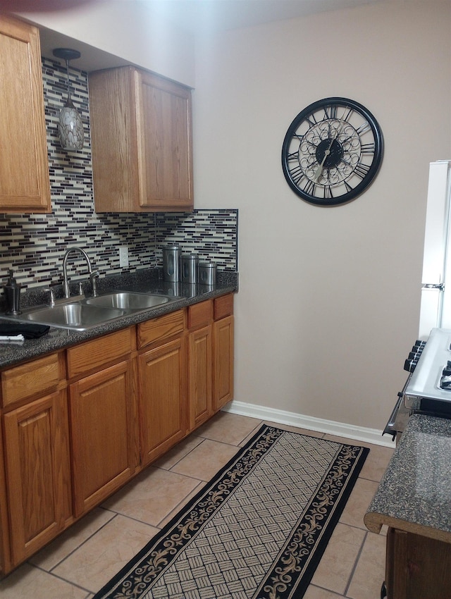 kitchen featuring light tile patterned flooring, sink, backsplash, white fridge, and range