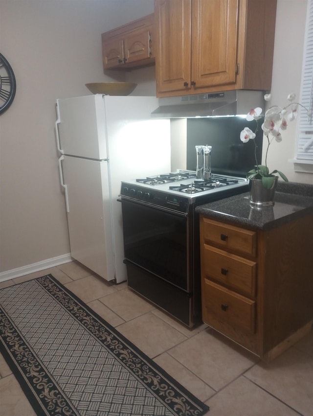 kitchen with light tile patterned flooring, black range with gas stovetop, and white refrigerator