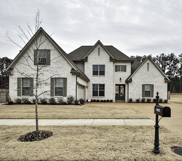 french country style house with a garage and a front lawn