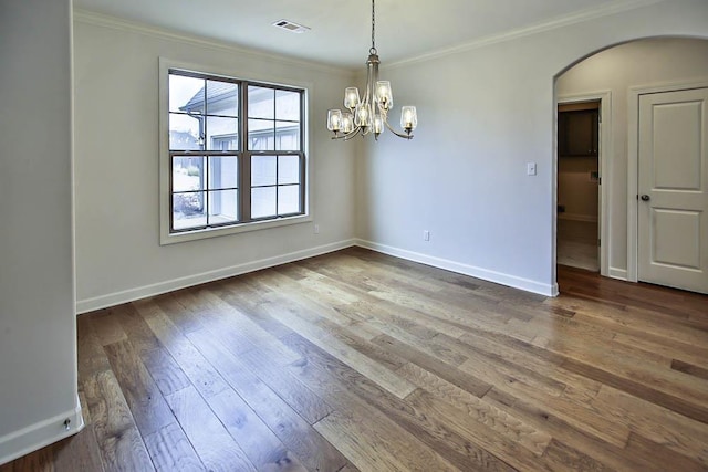 spare room featuring hardwood / wood-style flooring, crown molding, and a notable chandelier