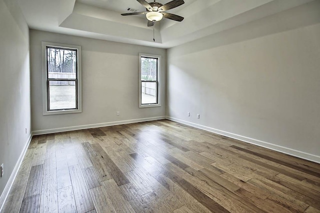 unfurnished room with a tray ceiling, wood-type flooring, and ceiling fan