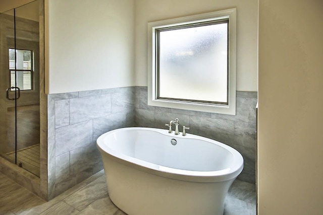 bathroom with tile walls and independent shower and bath