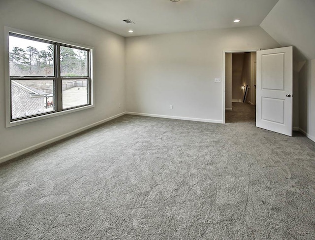 spare room featuring dark colored carpet and vaulted ceiling