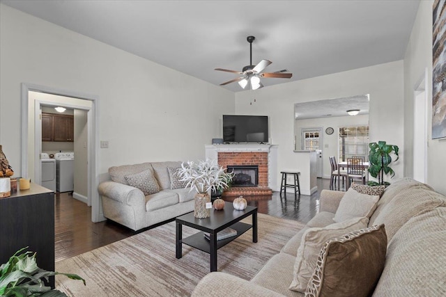 living room with a fireplace, dark wood-type flooring, washer and clothes dryer, and ceiling fan