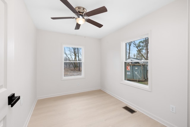 empty room with ceiling fan, light hardwood / wood-style floors, and a healthy amount of sunlight