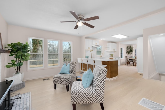 living area with sink, ceiling fan, and light wood-type flooring