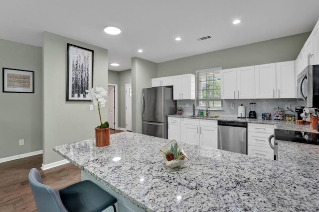 kitchen with sink, stainless steel appliances, white cabinets, and light stone countertops