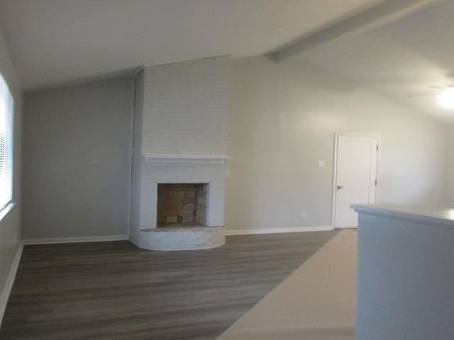 unfurnished living room featuring lofted ceiling with beams, a brick fireplace, and dark hardwood / wood-style floors