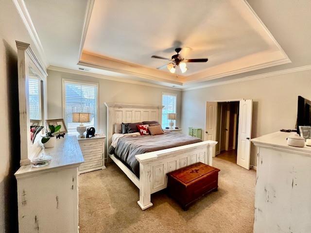 bedroom with a raised ceiling, ornamental molding, light carpet, and ceiling fan