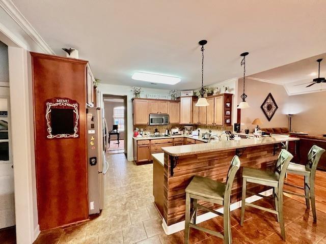 kitchen with a kitchen bar, crown molding, hanging light fixtures, appliances with stainless steel finishes, and kitchen peninsula