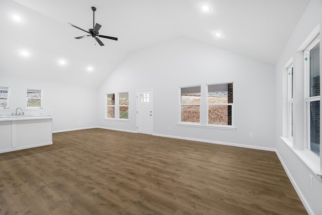 unfurnished living room with ceiling fan, dark wood-type flooring, sink, and high vaulted ceiling