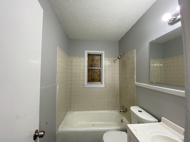 full bathroom with vanity, toilet, tiled shower / bath combo, and a textured ceiling