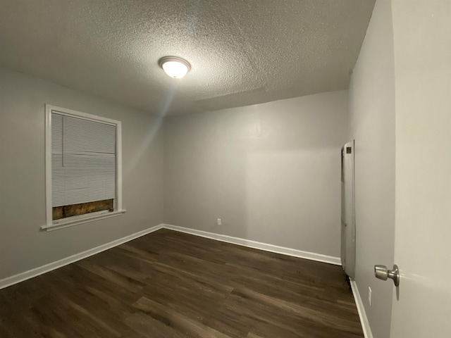 unfurnished room featuring a textured ceiling and dark hardwood / wood-style flooring