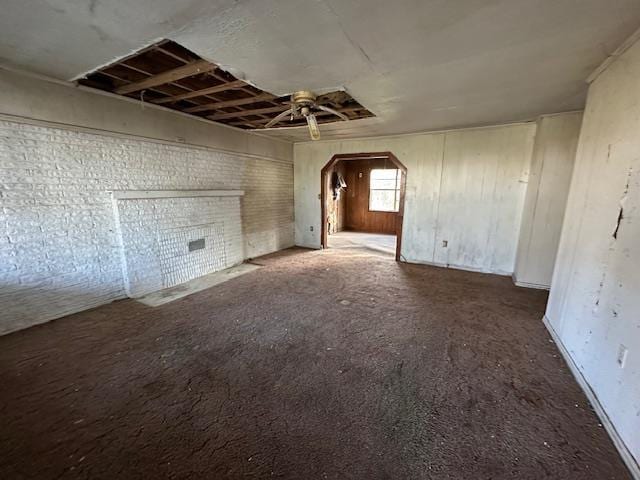 unfurnished living room with brick wall and ceiling fan