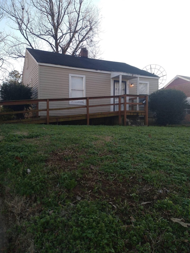 back of property with a wooden deck and a yard