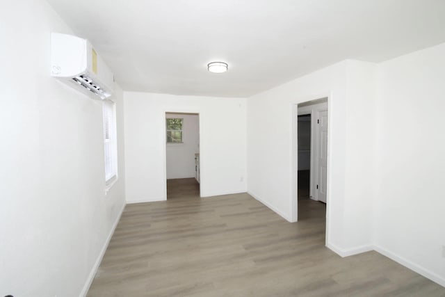 spare room featuring an AC wall unit and light wood-type flooring