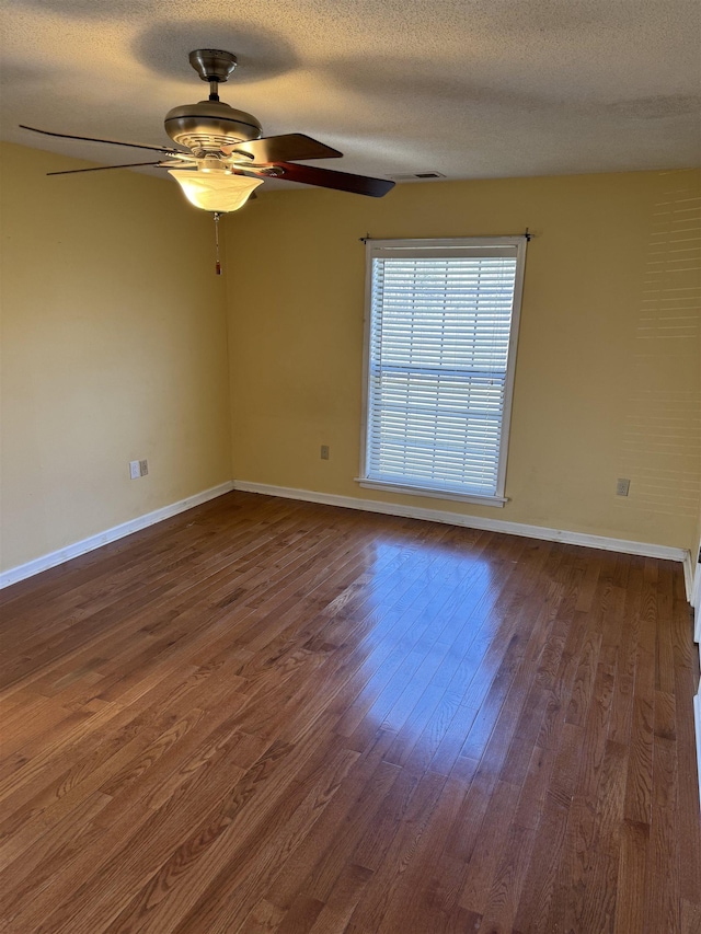 unfurnished room with a textured ceiling, dark wood-type flooring, and ceiling fan