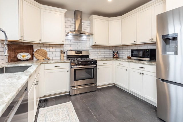 kitchen featuring appliances with stainless steel finishes, backsplash, light stone counters, wall chimney range hood, and white cabinets